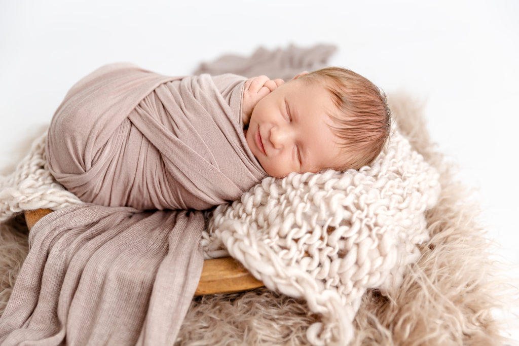 Newborn boy wrapped in swaddle for newborn portrait session