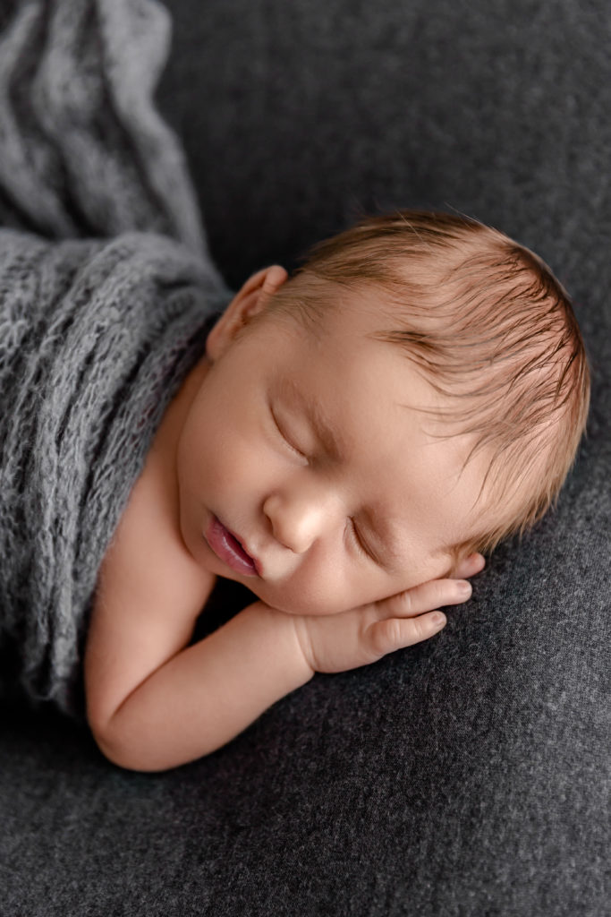 Newborn boy wrapped in swaddle for newborn portrait session